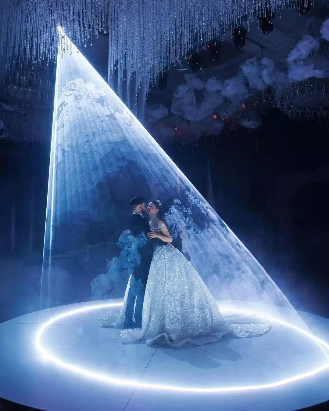 Couple sharing their first dance inside a cone of laser light