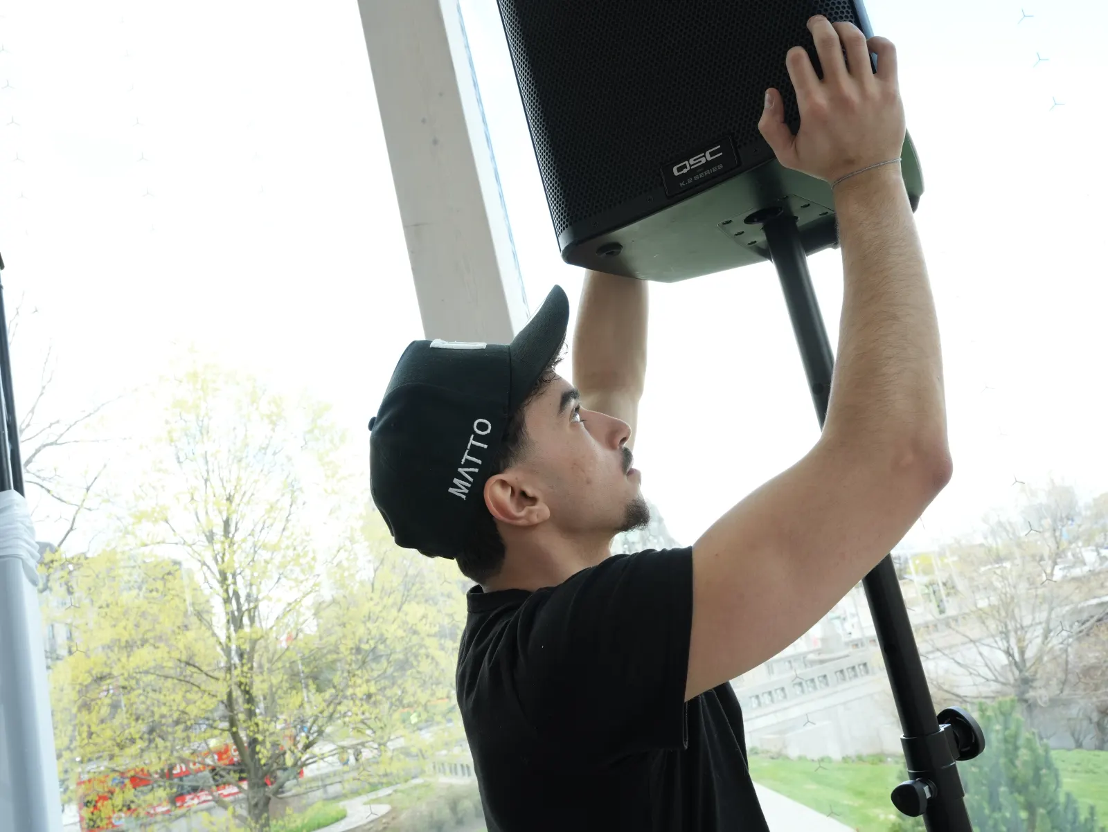 Technician mounting a QSC speaker on its stand